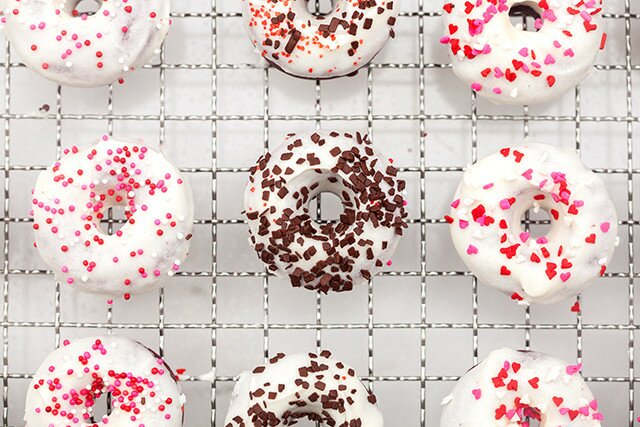 These little donuts contain extra cocoa powder for a more chocolatey red velvet. A cream cheese glaze and lots of sprinkles make them extra cute! | www.spachethespatula.com #recipe