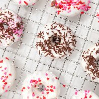 These little donuts contain extra cocoa powder for a more chocolatey red velvet. A cream cheese glaze and lots of sprinkles make them extra cute! | www.spachethespatula.com #recipe