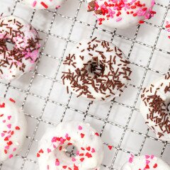 These little donuts contain extra cocoa powder for a more chocolatey red velvet. A cream cheese glaze and lots of sprinkles make them extra cute! | www.spachethespatula.com #recipe