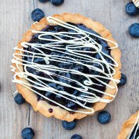 Buttery, crunchy tart shells filled with gooey, fresh blueberry filling and a white chocolate drizzle! | www.spachethespatula.com #recipe