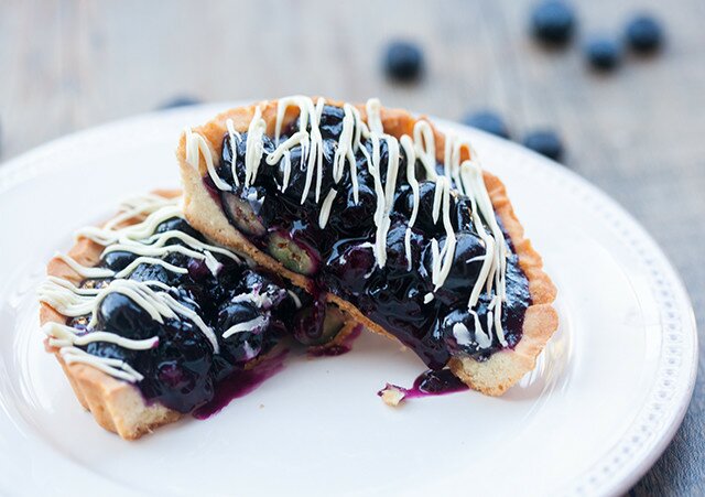 Buttery, crunchy tart shells filled with gooey, fresh blueberry filling and a white chocolate drizzle! | spachethespatula.com #recipe